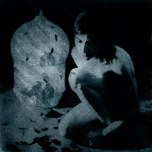 autoportrait-femme-nue-accroupie-et-cage-oiseau-en-arrière-plan-bromoil-bleu-nuit